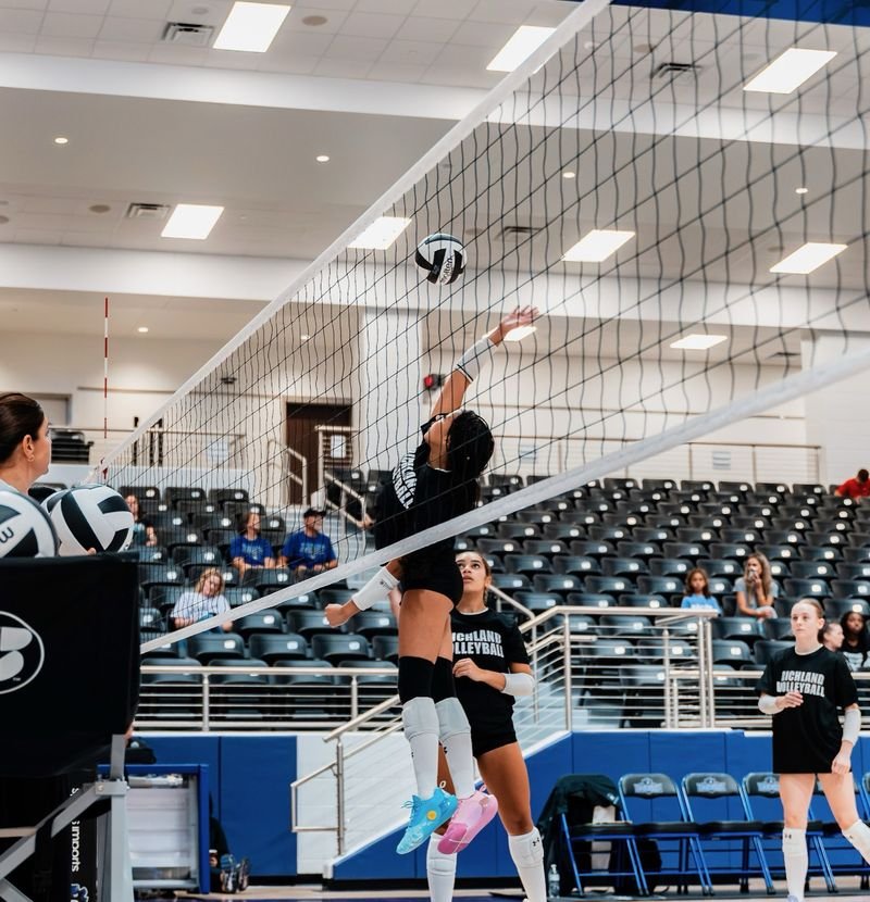 Arielle Akinwumi, number 9, reaching to attack over the net