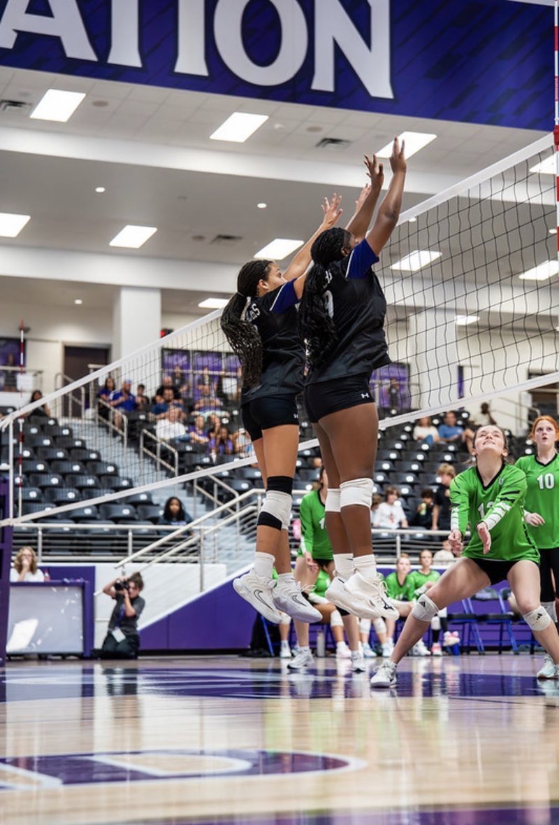 Arielle Akinwumi, number 9, jumping beside a teammate to block at the net